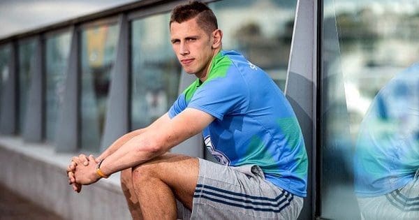 blog picture of young man sitting next to a building looking at the camera