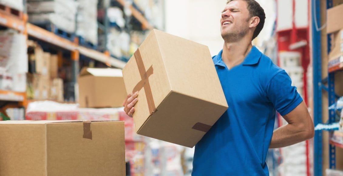 worker with backache while lifting box in the warehouse
