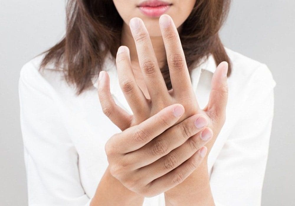 Woman massages her hand to relieve hand pain.
